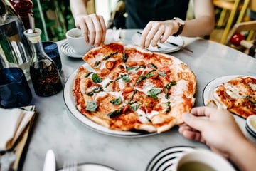close up of couple getting and sharing slices of freshly made pizza and enjoying meal in an italian restaurant