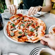 close up of couple getting and sharing slices of freshly made pizza and enjoying meal in an italian restaurant