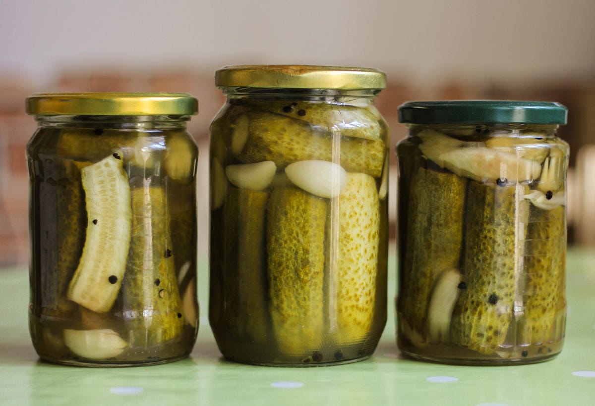 close up of cucumbers in glass jar on table