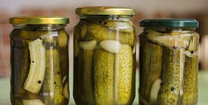 close up of cucumbers in glass jar on table