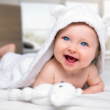 close up of cute baby smiling while lying on bed