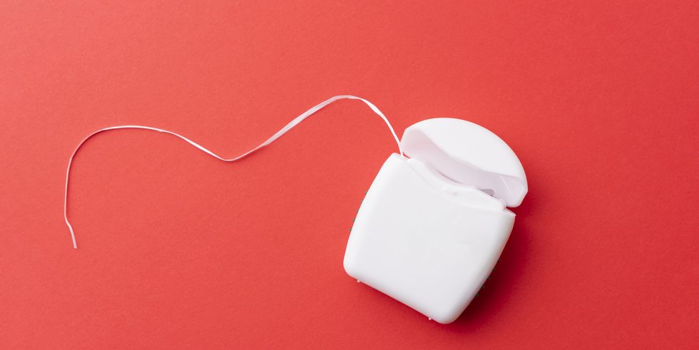 close up of dental floss on pink background