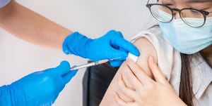 close up of doctor or nurse giving shot of covid19 vaccine to a patient's shoulder