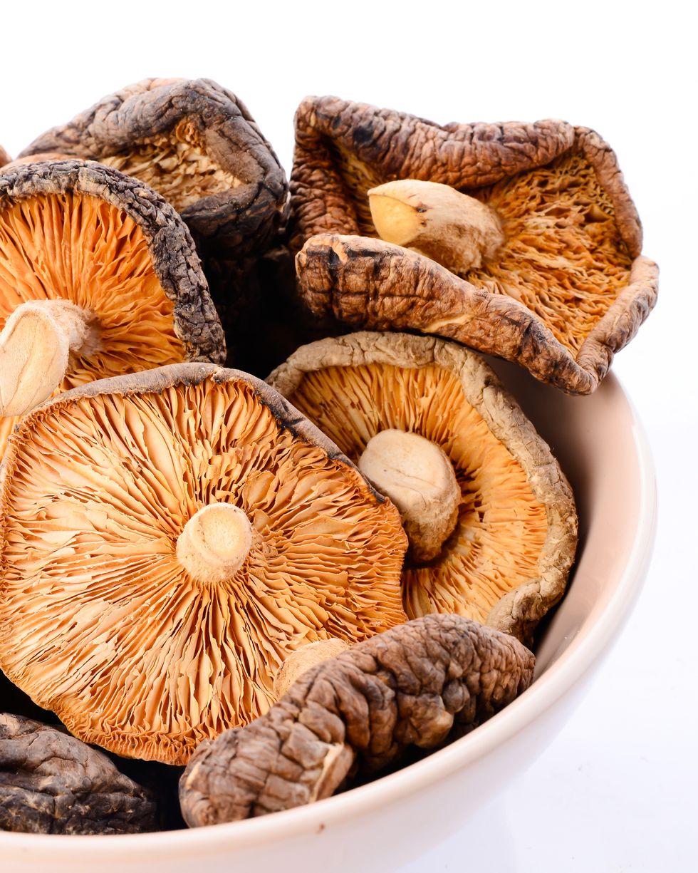 close up of dried mushrooms in bowl against white background