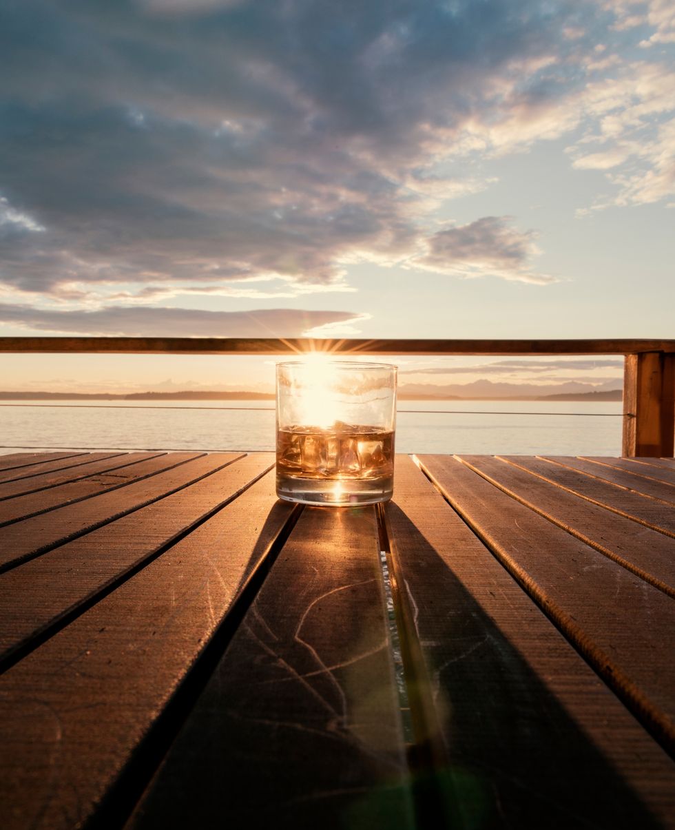 Close-Up Of Drink In Glass On Table Against Sky During Sunset