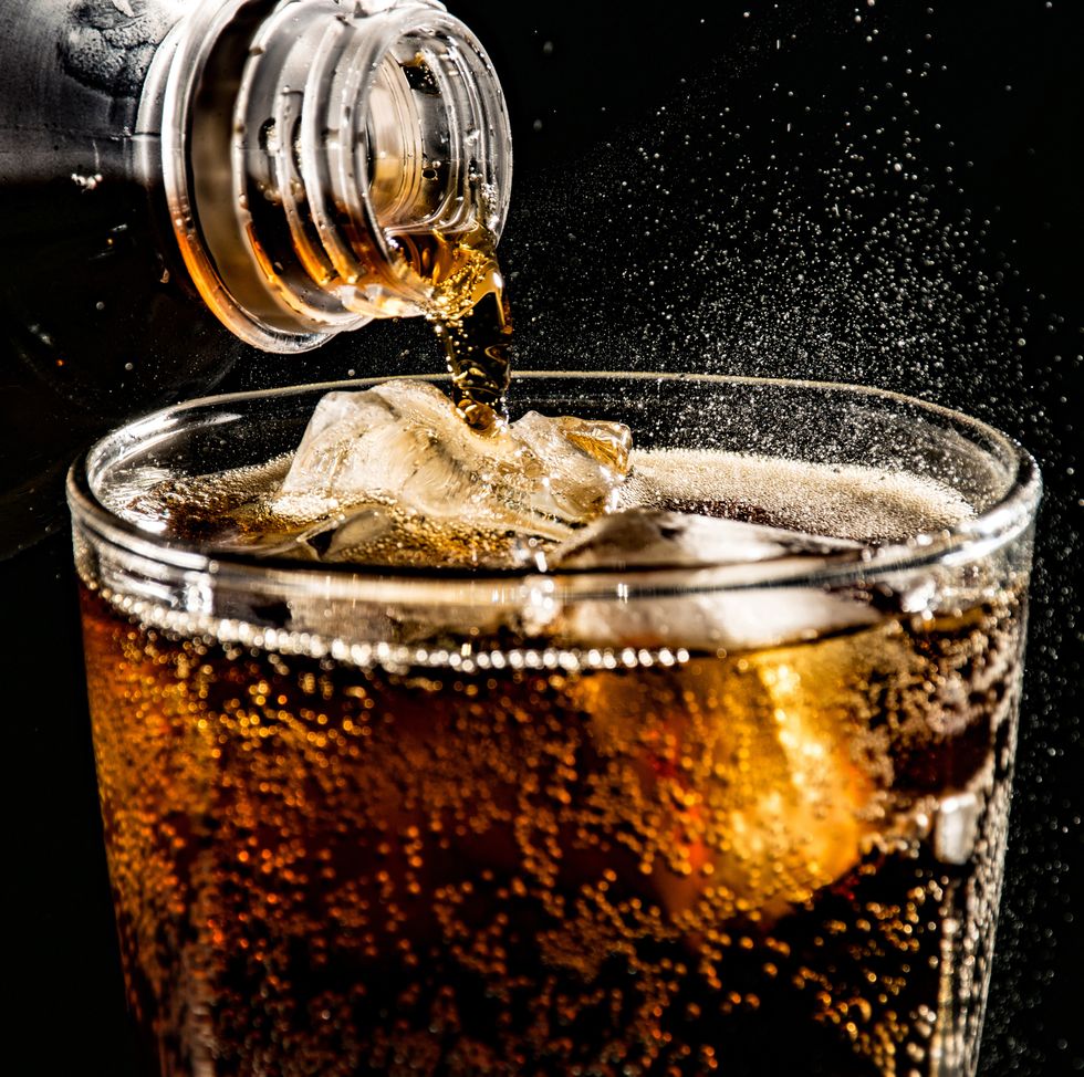 close up of drink pouring in drinking glass against black background
