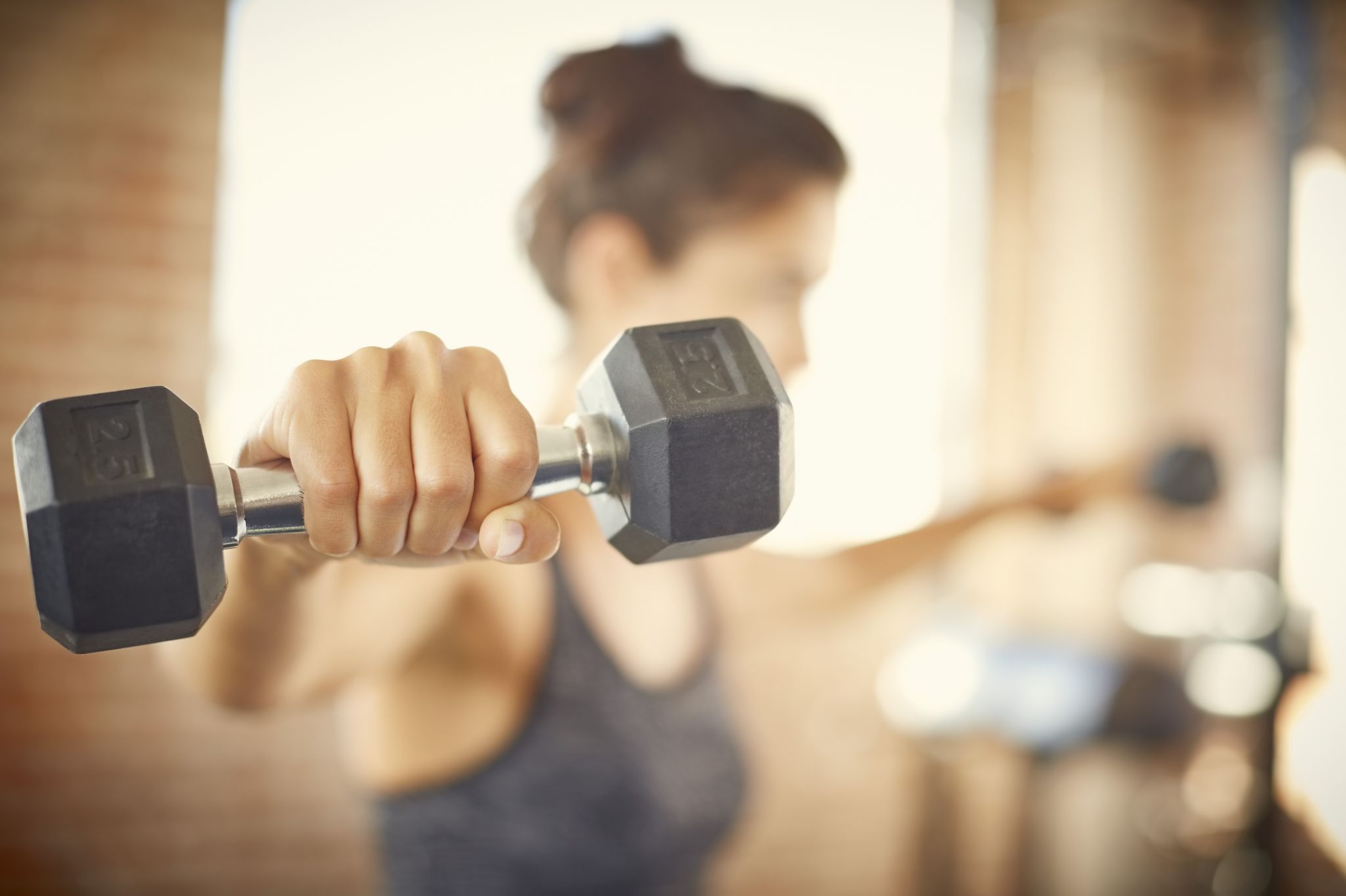 close up of dumbbell held by young woman in gym