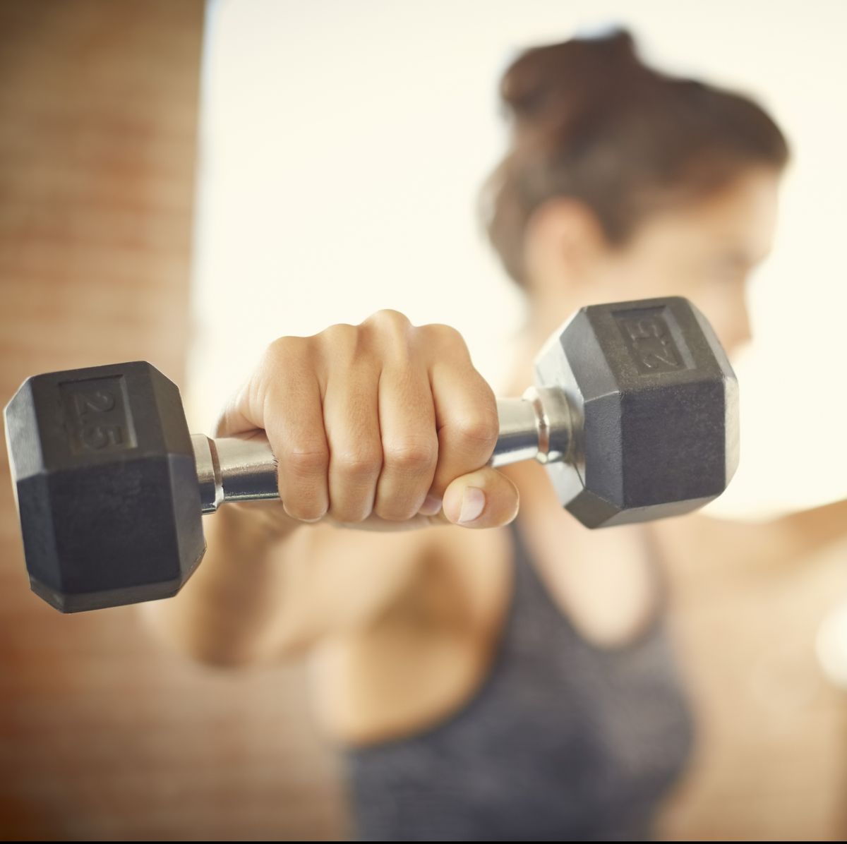 Close-up of dumbbell held by young woman in gym