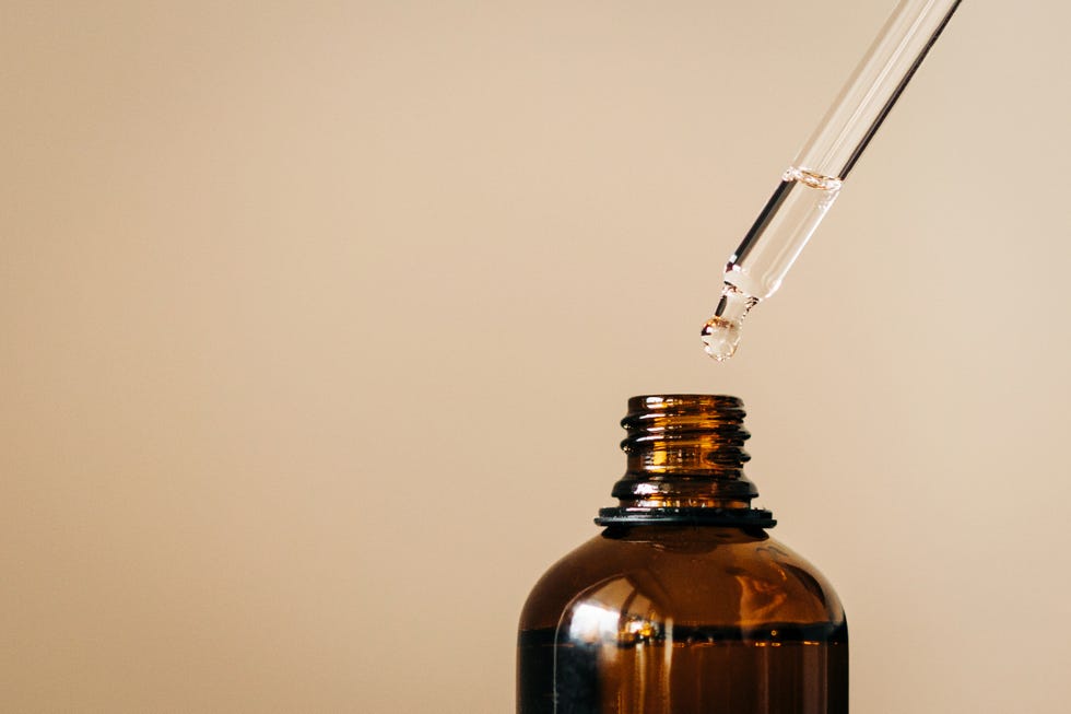 close up of face serum pouring from a pipette into an amber glass bottle natural skincare and essential oil aromatherapy health and wellness concept copy space