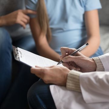 close up of female doctor making notes in patient card