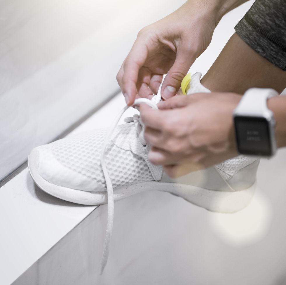 close up of female hands tying sneakers with smartwatch