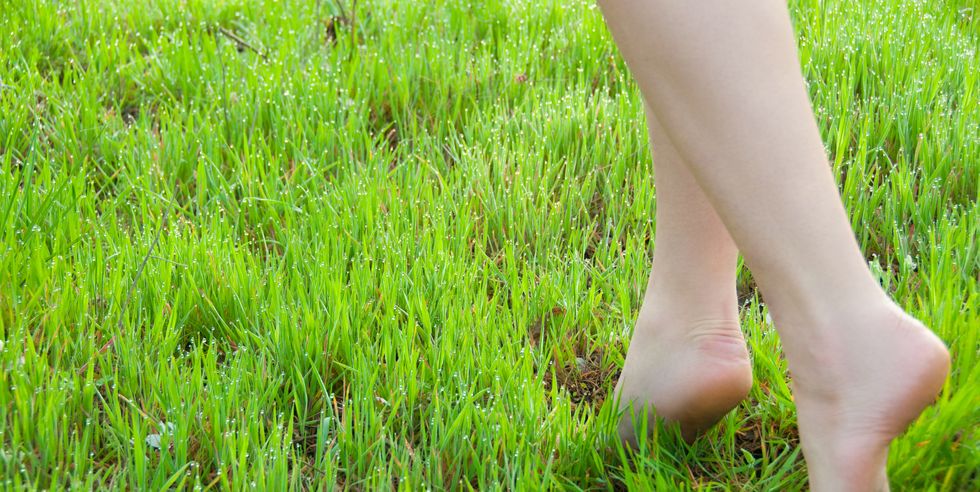close up of female legs walking on green grass barefoot