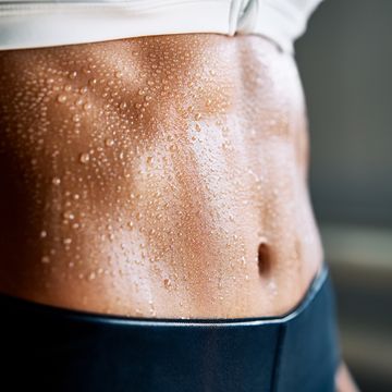 close up of fit woman torso with sweat on skin after workout