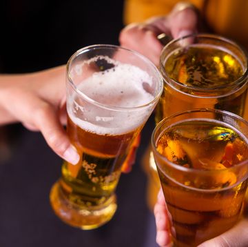 close up of friends clinking glasses of beer, celebrating together at a bar.the lively atmosphere captures laughter, camaraderie,good times, as young friends enjoy a night out with refreshing drinks