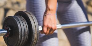 closeup of girl lifting a weightlifting barbell
