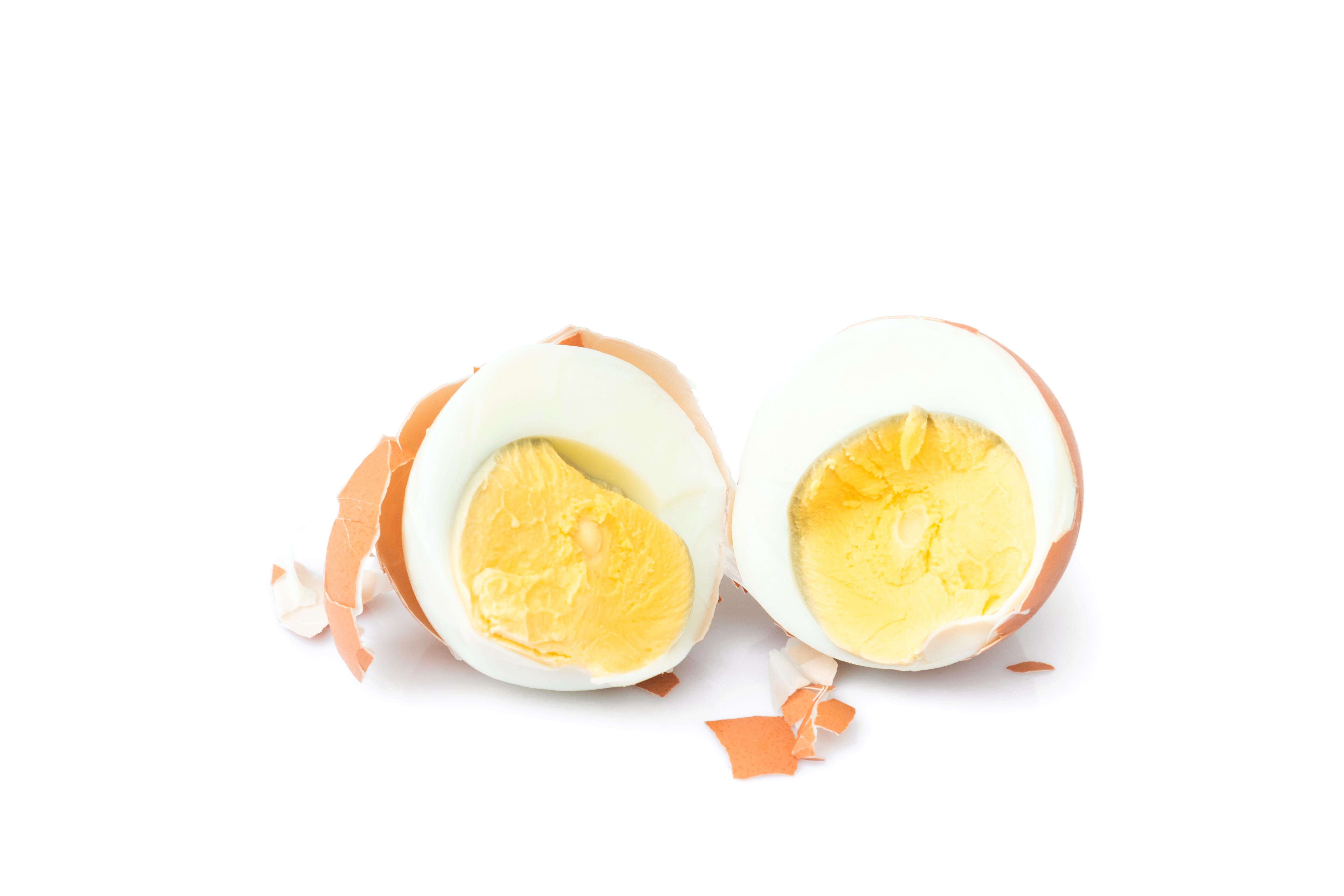 Close-Up Of Halved Boiled Egg Over White Background