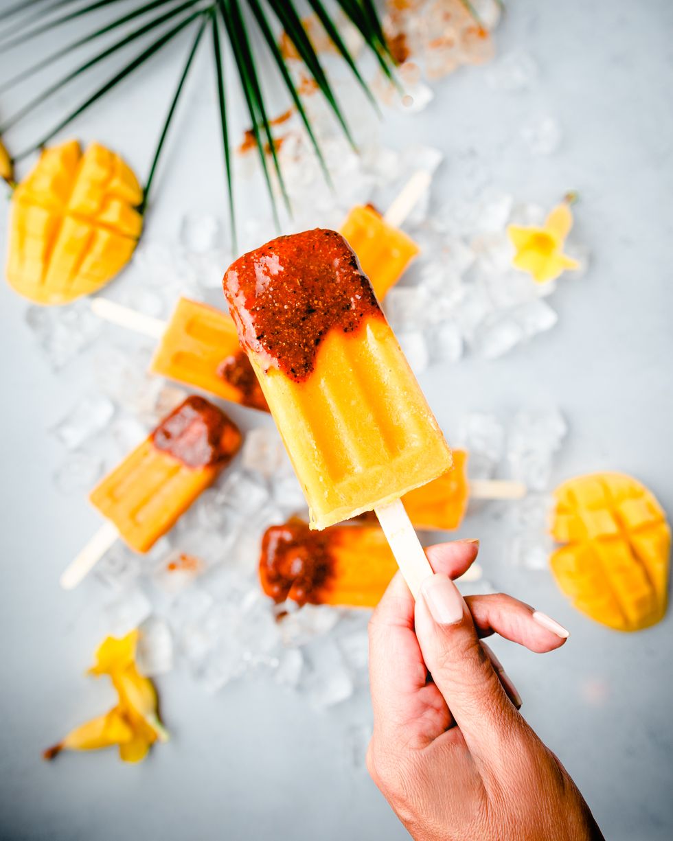 close up of hand holding a mango popsicle
