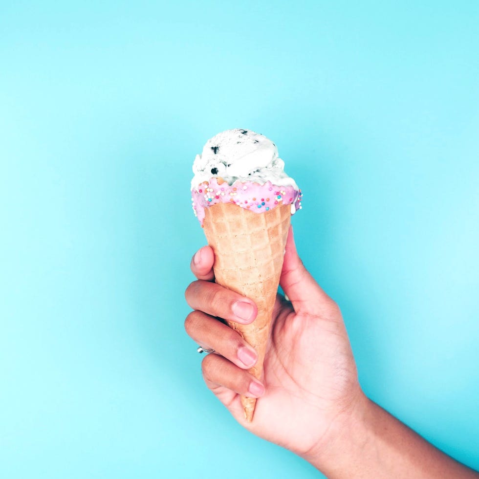 Close-Up Of Hand Holding Ice Cream Against Blue Background