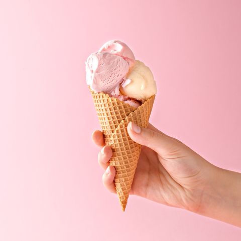 Close-Up Of Hand Holding Ice Cream Against Pink Background