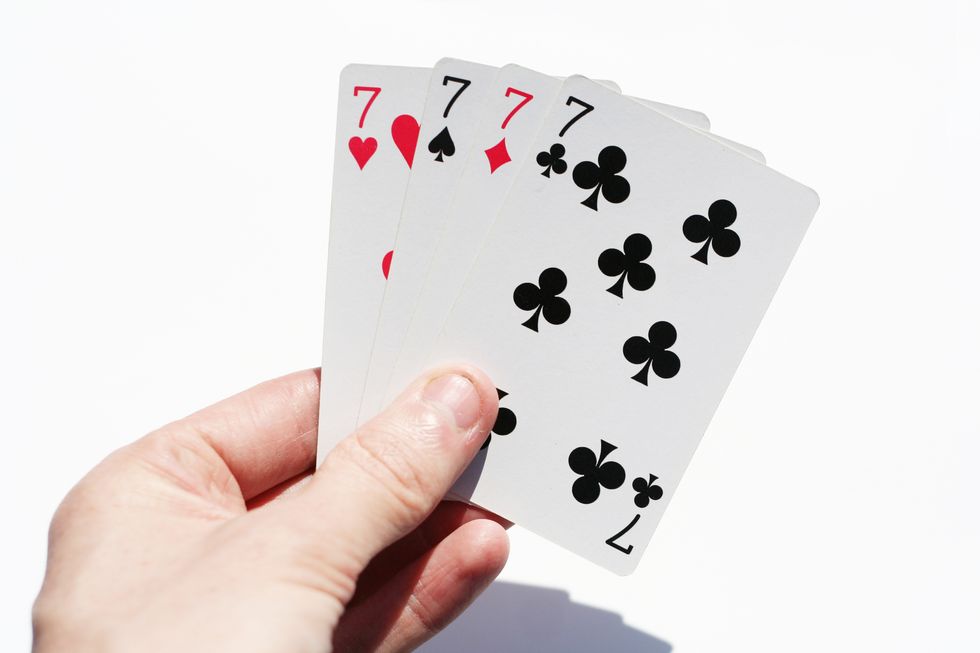 close up of hand holding playing cards over white background