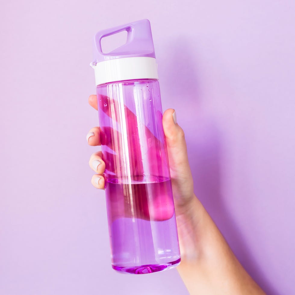 Close-Up Of Hand Holding Water Bottle Against Colored Background Close-Up Of Hand Holding Water Bottle Against Colored Background