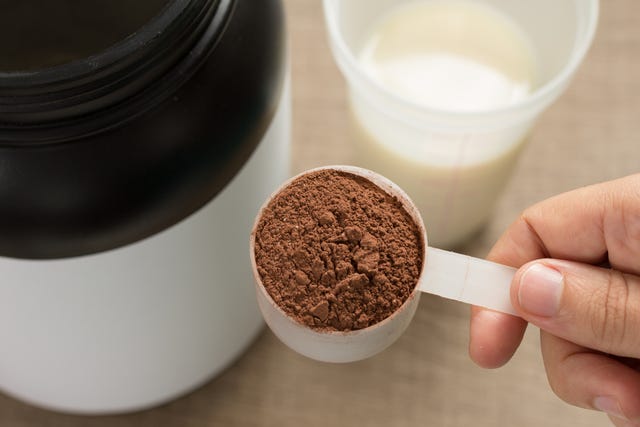 close up of hand holding whey cup on table