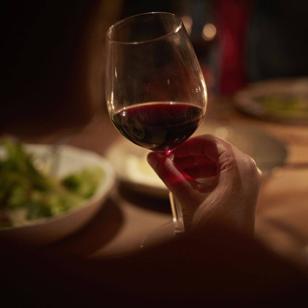 close up of hand holding wine glass at late dinner
