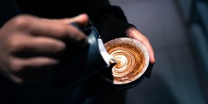 close up of hand pouring coffee latte art