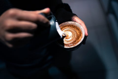 close up of hand pouring coffee latte art