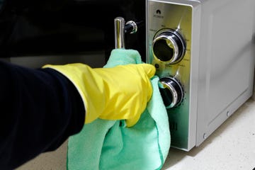 close up of hand with rubber glove cleaning microwaves