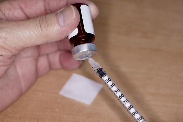 close up of handheld needle and syringe with testosterone vial