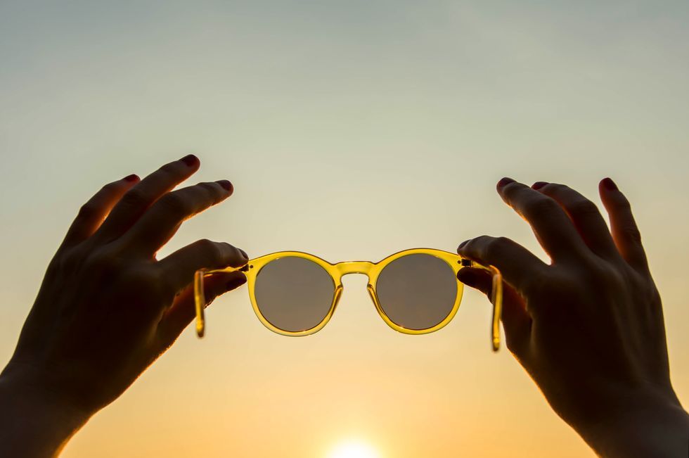 Close-Up Of Hands Holding Sunglasses Against Clear Sky