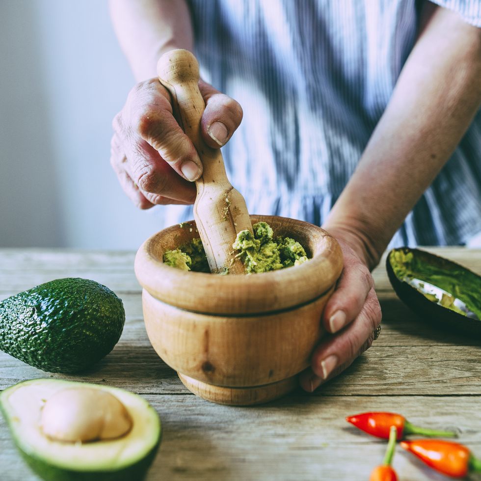 closeup of hands making homemade guacamole