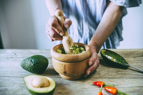 closeup of hands making homemade guacamole