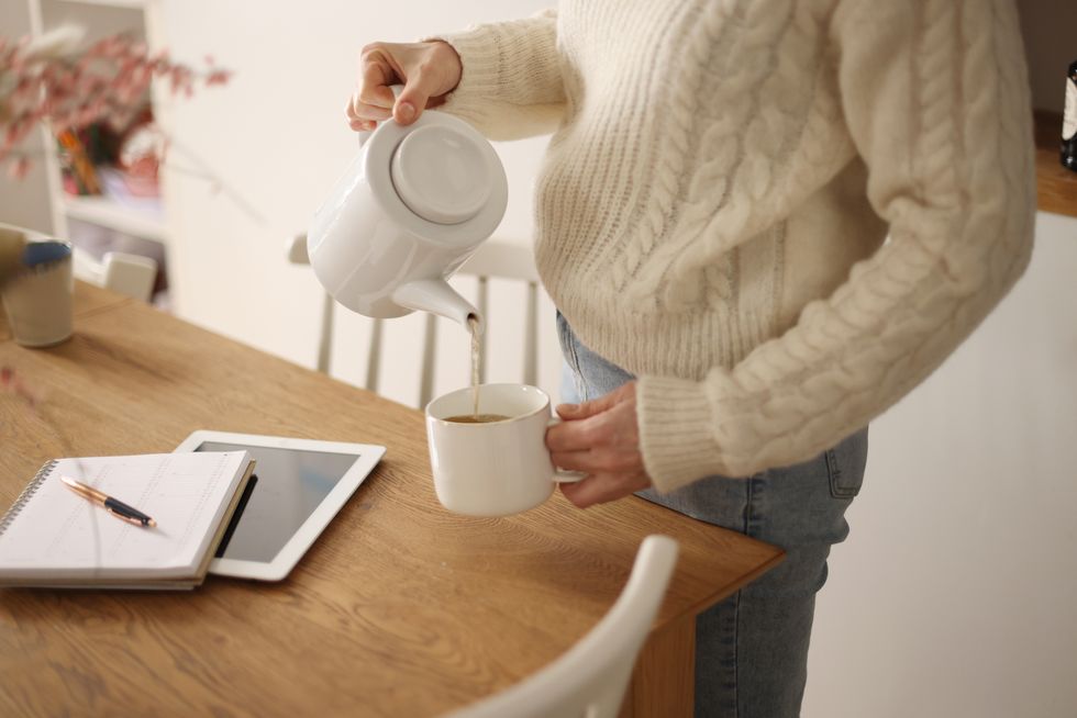 close up of hands serving a cup of tea, in an atmosphere of work at home