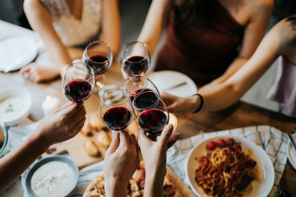 close up of happy young friends having fun and toasting and celebrating with red wine during party