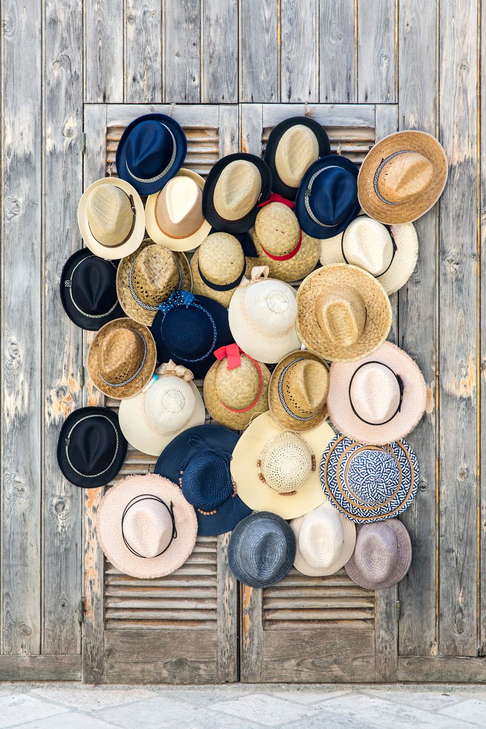 close up of different kinds of hats hanging on two weathered slatted door