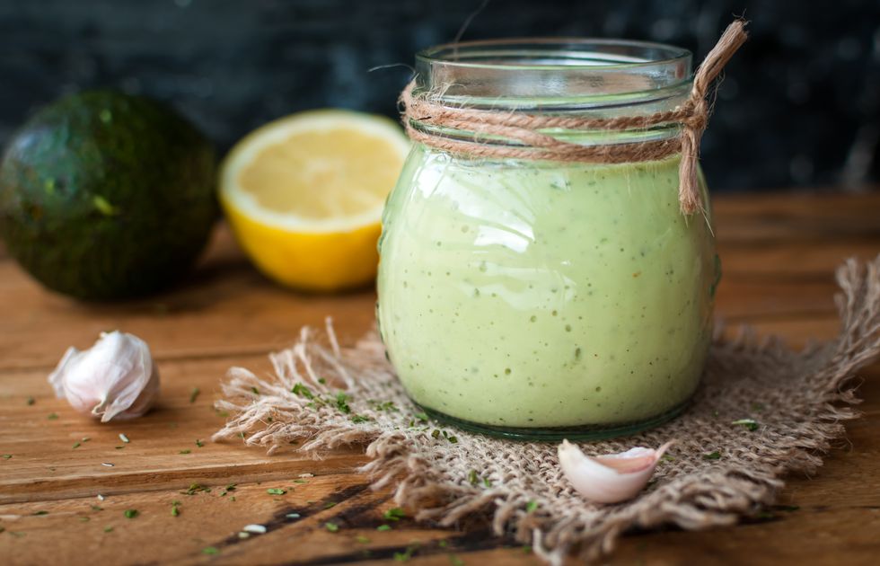 close up of homemade creamy avocado dressing in a jar on wooden background