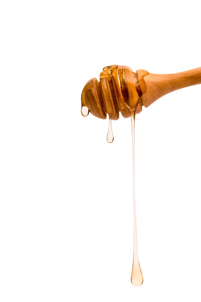 Close-Up Of Honey Dripping Off Against White Background