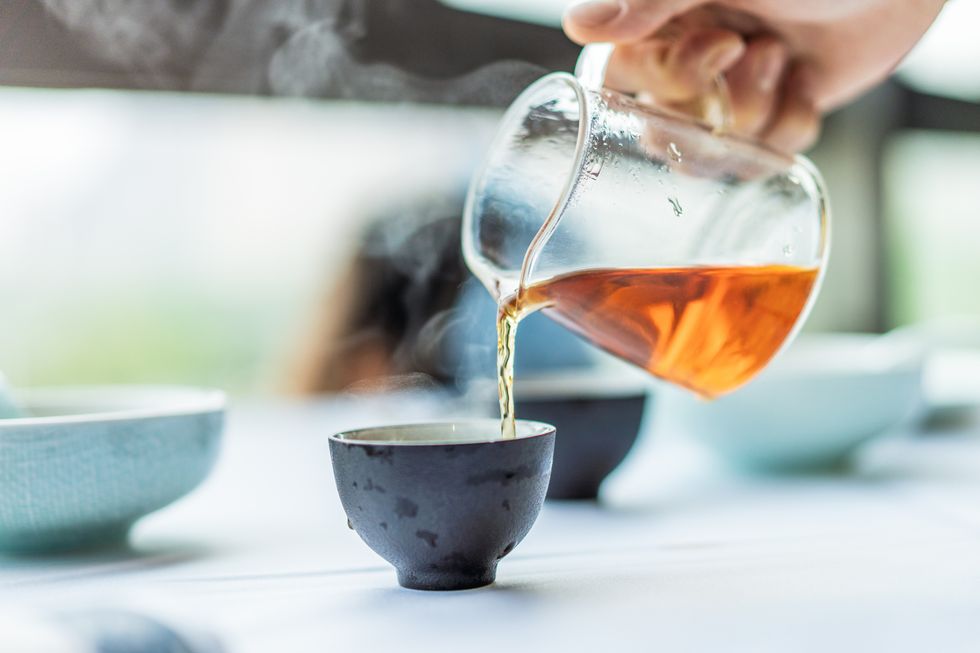 close up of human hands serving chinese tea