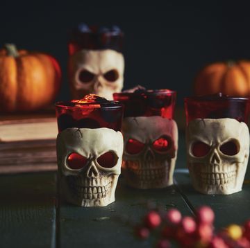 close up of human skull candles and orange pumpkins on a table