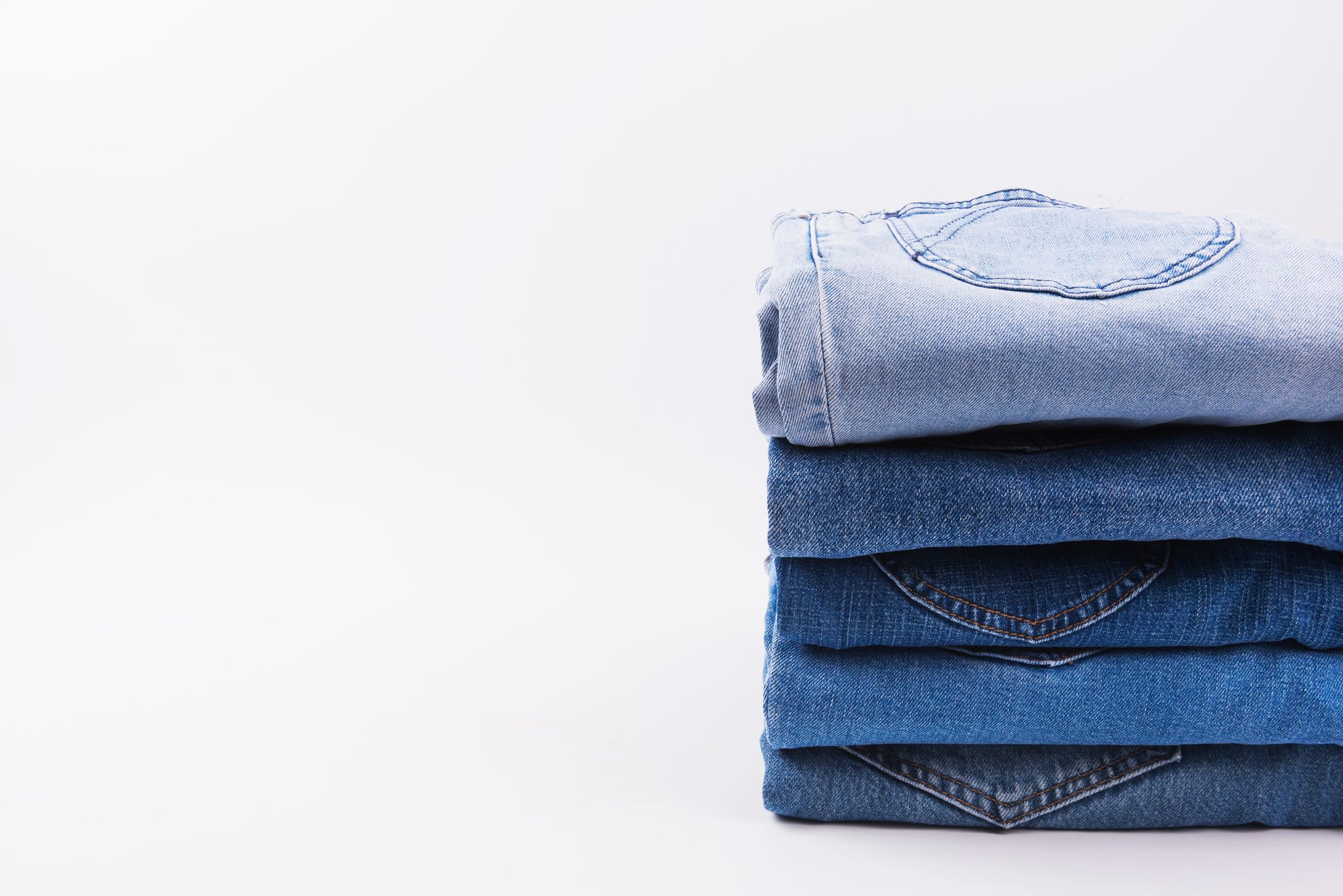 Close-Up Of Jeans Stacked Against White Background