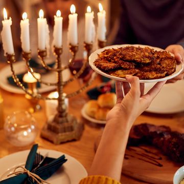 close up of jewish couple passing food at dining table on hanukkah
