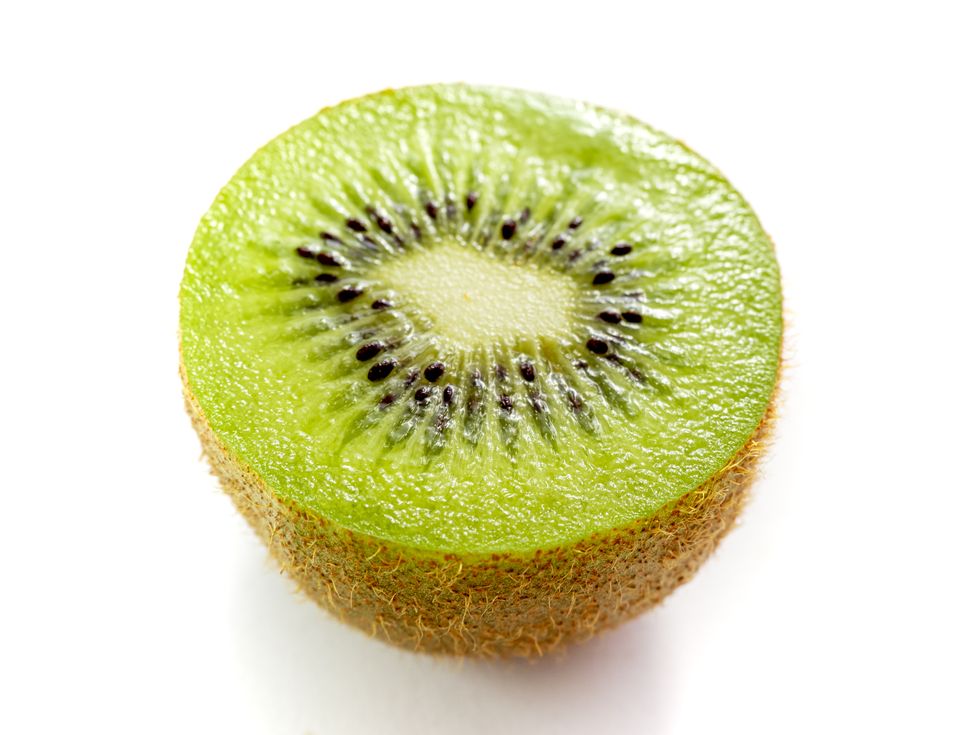 close up of kiwi half over white background