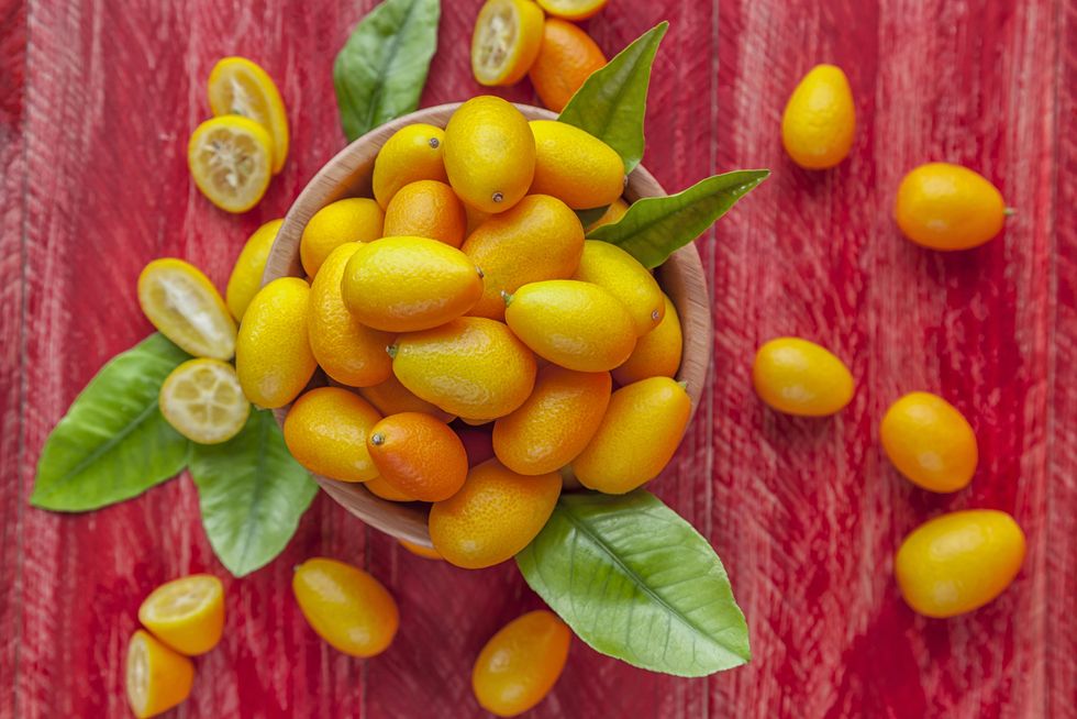 close up of kumquats in bowl on red wooden table