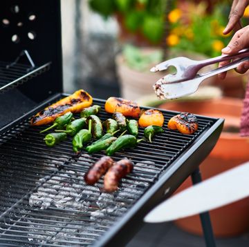 close up of man barbecuing chilli peppers on grill