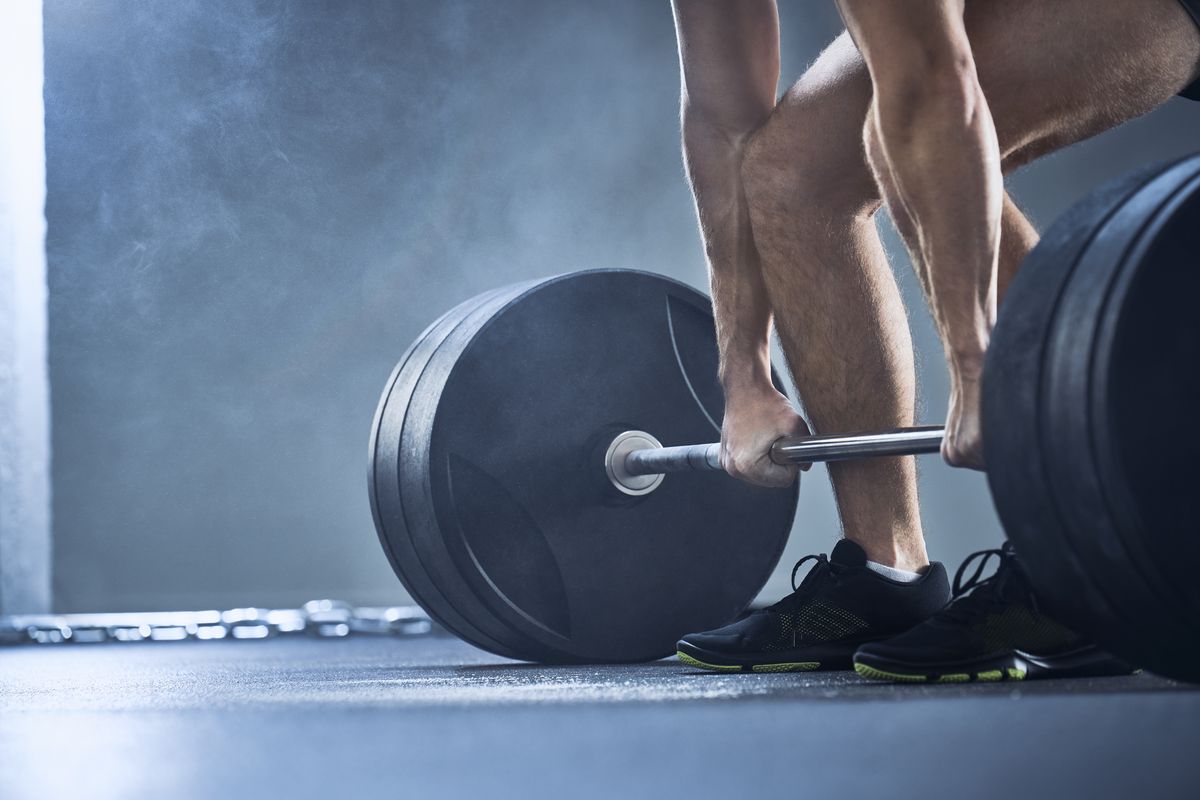 close up of man doing deadlift exercise at gym
