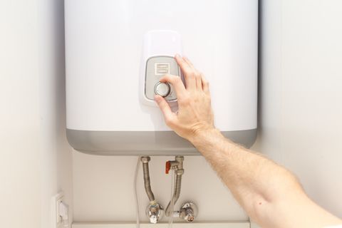 Close-up of man hands setting the temperature of water in Electric Boiler