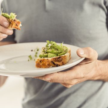 close up of man holding a plate with a healthy avocado bread