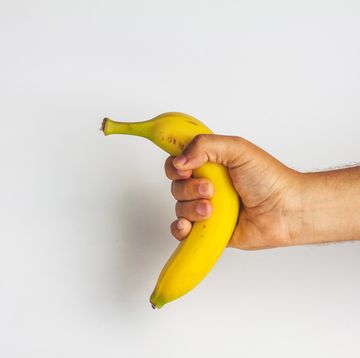 close up of man holding banana against white background